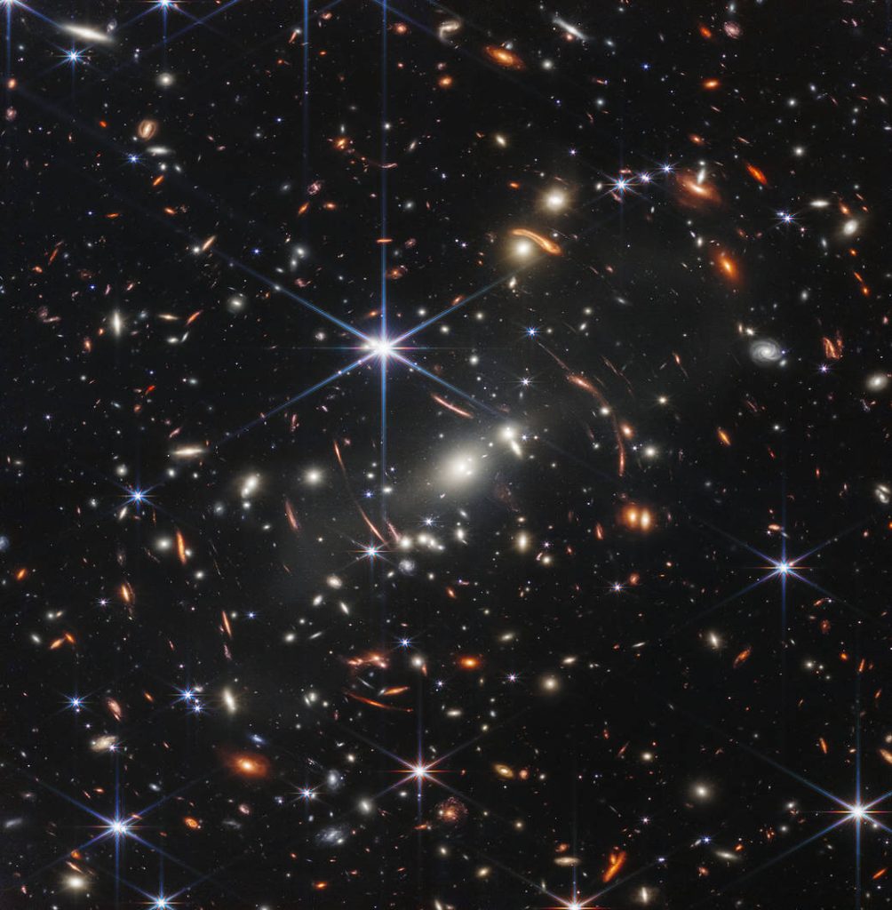 Thousands of orange and white galaxies on the black background of space